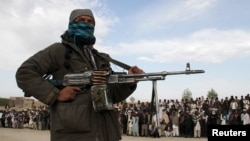  A member of the Taliban stands with others at the execution of three men in Ghazni Province, April 18, 2015. Residents of the area say Islamic State has threatened them to stop supporting the Taliban and support Islamic State instead.