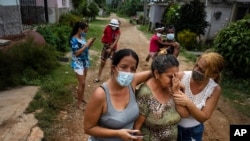 Zuleydis 'Zuly' Elledias, right, along with her sister Sudenis, comfort their mother who cries for missing relatives who disappeared when they ventured out in a homemade boat in an attempt to reach Florida, in Orlando Nodarse, June 30, 2021.