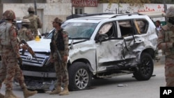 Pasukan paramiliter Pakistan berkumpul di sebelah kendaraan yang hancur di lokasi pemboman bunuh diri di Quetta, Pakistan, Sabtu, 25 November 2017.