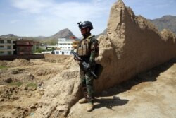 FILE - An Afghan commando stands guard at the site of a suicide bomb attack on the outskirts of Kabul, April 29, 2020.