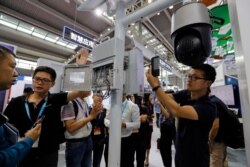 FILE - Visitors look at the 5G mobile station and a surveillance camera by China's telecoms equipment giant Huawei on display at the China Public Security Expo in Shenzhen, China's Guangdong province, Oct. 29, 2019.