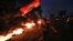 A protester runs holding an Iraqi flag as tires burn during a demonstration demanding better public services and jobs in Basra, southeast of Baghdad, Iraq, July 27, 2020. 