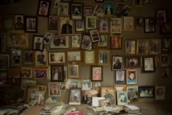 In this Sept. 12, 2019 photo, pictures of Yazidis slain in 2014 by IS militants are found in a room at the Lalish shrine in Iraq. When Yazidis were seized alive by the militants, commanders registered them, and decided where they would be sent.