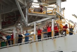 Crew members of Turkey's 230-meter (750-foot) drillship 'Yavuz' wave as the ship leaves the port of Dilovasi, June 20, 2019.