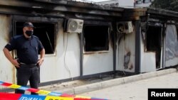 A police officer stands near a burnt field hospital for COVID-19 patients after a fire broke out at the facility, in Tetovo, North Macedonia, Sept. 9, 2021.