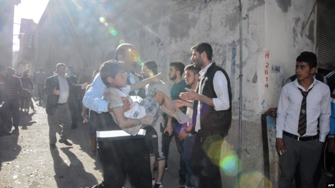FILE - A man carries an injured child after four rockets fired from Syria slammed into the southern Turkish town of Kilis, killing four Syrians — including three children — in the latest deadly cross-border strike to panic residents, April 18, 2016.
