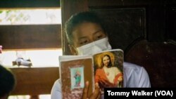 ফাইল - থাইল্যান্ডের উমফাং, খ্রিস্টান গণ সমাবেশের সময় একজন কারেন মহিলা একটি স্তোত্রের বই হাতে ধরে রেখেছেন।২৩ মে ২০২১। 