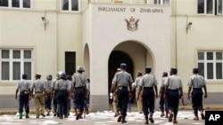 Zimbabwean police officers clear pamphlets left after a demonstration protesting delays in the drafting of a new constitution outside the parliament in Harare, Tuesday, Sept. 11, 2012. 