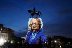 FILE - An image of the late Georgia Congressman and civil rights pioneer U.S. Rep. John Lewis is projected on to the pedestal of the statue of confederate Gen. Robert E. Lee on Monument Avenue in Richmond, Va., July 22, 2020.