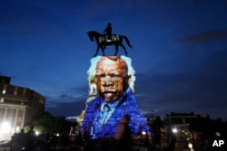 FILE - An image of the late Georgia Congressman and civil rights pioneer U.S. Rep. John Lewis is projected on to the pedestal of the statue of confederate Gen. Robert E. Lee on Monument Avenue in Richmond, Va., July 22, 2020.