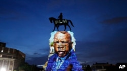 An image of the late Georgia Congressman and civil rights pioneer U.S. Rep. John Lewis is projected on to the pedestal of the statue of confederate Gen. Robert E. Lee on Monument Avenue, July 22, 2020, in Richmond, Va. 