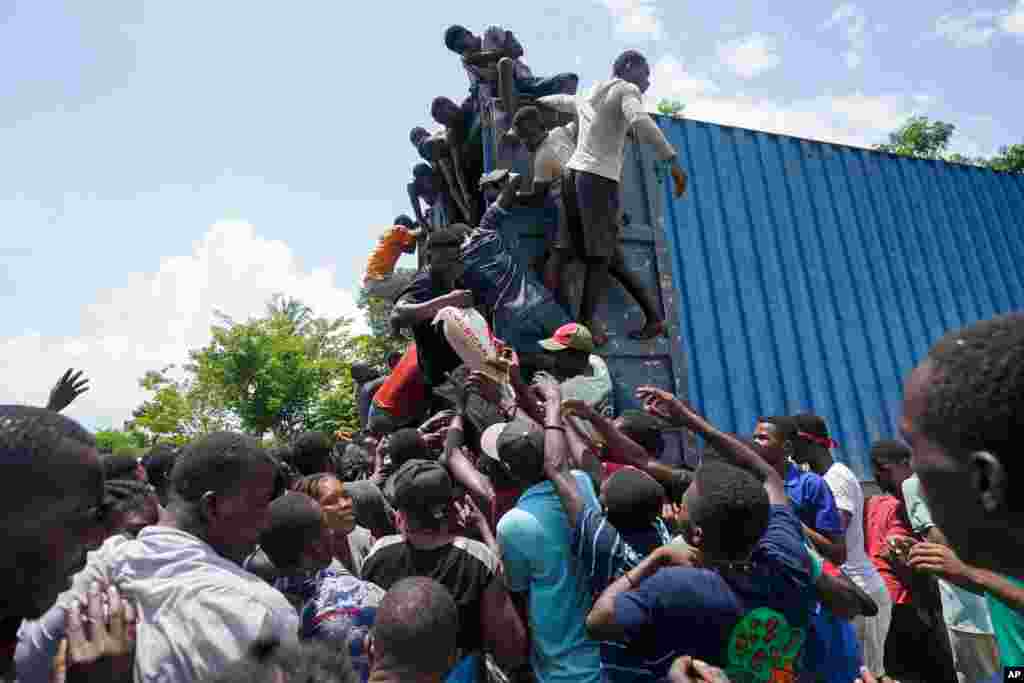 아이티 비테르 주민들이 미국 정부에서 지진 피해자들을 위해 보낸 구호물자 컨테이너에 매달려있다.