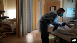 Chaplain Elias Mena holds the hand of a COVID-19 patient while praying for him at Providence Holy Cross Medical Center in the Mission Hills section of Los Angeles, Jan. 15, 2021. 