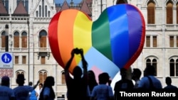FILE People gather in front of a huge rainbow balloon put up by members of Amnesty International and Hatter, an NGO promoting LGBT rights, at Hungary's parliament in Budapest, Hungary, July 8, 2021.
