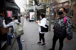 FILE - People wearing face masks prepare to board a bus on the first day of New Zealand's new coronavirus disease safety measure that mandates wearing of a mask on public transport, in Auckland, August 31, 2020.