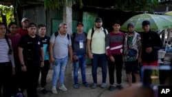 Migrantes venezolanos hacen fila para que un contrabandista les tome una foto como prueba de que pagaron la tarifa de pasaje para cruzar de Tecún Umán, Guatemala a Tapachula, México, el 29 de octubre de 2024.