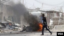 ຜູ້ຊາຍຄົນນຶ່ງ ກໍາລັງເວົ້າໂທລະສັບ ຢ່າງຜ່ານບ່ອນວາງລະເບີດ ໃກ້ທາງເຂົ້າສະໜາມບິນນາໆຊາດ ທີ່ໂຊມາເລຍ