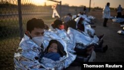 Dustin, seorang pencari suaka dari Honduras, memeluk putranya, Jarrardo, di dekat sebuah lapangan baseball di La Joya, Texas, setelah menyeberang sungai Rio Grande ke wilayah Amerika Serikat dari Meksiko, menggunakan rakit, Jumat, 19 Maret 2021. (Foto: Adrees Latif/Reuters)