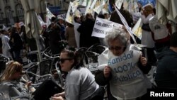 A woman wearing a vest reading "100% public health care" attends a protest by doctors to demand better salaries and working conditions, in Madrid, March 21, 2018.