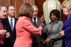 FILE - Rep. Maxine Waters, D-Calif., holds up a pen used by House Speaker Nancy Pelosi to sign the resolution to transmit two articles of impeachment against President Donald Trump to the Senate for trial on Capitol Hill, Jan. 15, 2020.