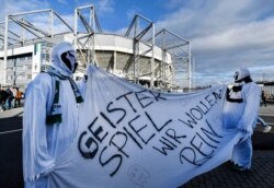 Borussia fans dressed as ghosts hold a banner reading "Ghost match - we want in" prior the German Bundesliga soccer match in Moenchengladbach, Germany, March 11, 2020. The match was played without spectators due to the coronavirus.