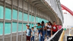 FILE - Residents with visas cross the Puerta Mexico bridge to enter the U.S., in Matamoros, Mexico, June 28, 2019. U.S. President Joe Biden on May 14, 2021, revoked a Trump-era proclamation that sought to bar entry of immigrants without health coverage.