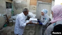 Jordanian volunteers from Tikiyet Um Ali charity, right, hand meals to a poor family in an impoverished neighborhood in the heart of downtown Amman Sept. 5, 2010.