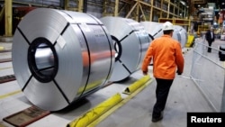 FILE - A worker walks by rolled up steel sits in the ArcelorMittal Dofasco steel plant in Hamilton, Ontario, Canada, March 13, 2018. 