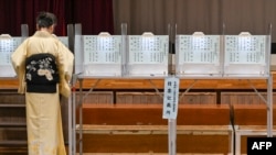 FILE - A woman in a traditional kimono votes during the general election at a polling station set up at a local school in Tokyo on October 27, 2024.