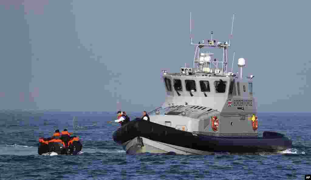 A Border Force vessel assists a group of people thought to be migrants on board from their inflatable dinghy in the English Channel. The British government tries to curb the number of people crossing from France in small boats.