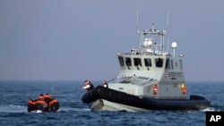 A Border Force vessel assists a group of people thought to be migrants on board from their inflatable dinghy in the English Channel, Aug. 10, 2020. The British government tries to curb the number of people crossing from France in small boats.