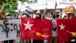 Protesters holding National League for Democracy (NLD) flags raise three-finger salutes during flash protests against the military coup at Bahan township in Yangon, Myanmar, June 25, 2021. 
