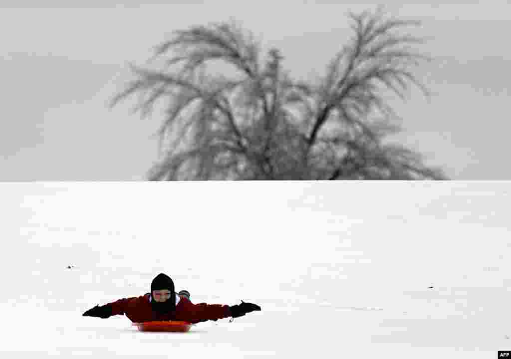 Caelan Brooks, 12, of Plano, Texas, glides down a hill at Hoblitzelle Park in Plano, Texas. The ice storm that has hit North Texas, left over 250,000 residents and businesses without power and has led to more than 1,700 flight delays and cancellations across the country.