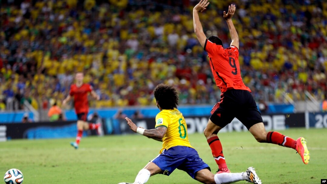 Mexico's Raul Jimenez, right, raises his arms after a challenge on Brazil's Marcelo during the group A World Cup soccer match between Brazil and Mexico at the Arena Castelao in Fortaleza, Brazil, Tuesday, June 17, 2014