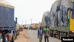 FILE—Truck drivers walk as trucks carrying food, humanitarian aid and industrial equipment wait due to sanctions imposed by Niger's regional and international allies, in the border town of Malanville, Benin August 18, 2023.