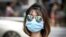 FILE - A woman wearing sunglasses and a mask to protect against the coronavirus walks on a street in Bangkok, Thailand, Feb. 13, 2020.
