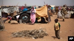 In this photo taken on March 9, 2014 and released by the United Nations African Union Mission in Darfur, a Sudanese family take shelter under their donkey cart at the Kalma refugee camp for internally displaced people, south of the Darfur town of Nyala, Sudan.