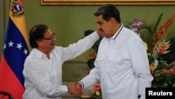 Los presidentes de Colombia y Venezuela, Gustavo Petro y Nicolás Maduro, estrechan sus manos sonrientes en una reunión en el Palacio de Miraflores, en Caracas, el 18 de noviembre de 2023.