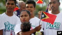 In this Friday, Aug. 30, 2019, photo, people wave East Timorese flags during the commemoration of the 20th anniversary of a referendum that secured its independence from Indonesia, in Dili, East Timor.