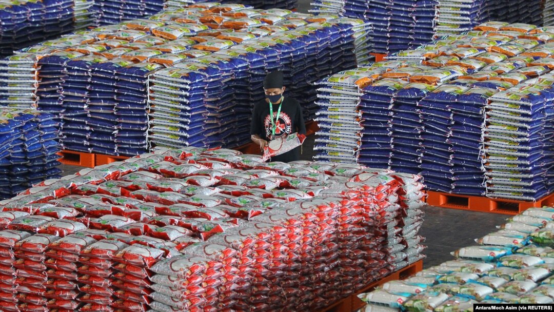 Seorang pekerja memakai masker pelindung saat menyusun tumpukan karung berisi beras, di tengah wabah COVID-19 di Surabaya, Jawa Timur, 20 April 2020. (Foto: Antara/Moch Asim via REUTERS)