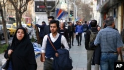 FILE - Amir Ali Najafi, center, a transgender man, walks on a sidewalk in Tehran, Iran, March 11, 2018. Transgender men and women can face harassment in Iran, despite a religious order acknowledging them. 