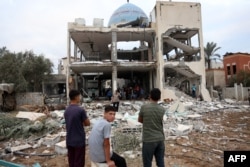 Warga Palestina menatap masjid yang diubah menjadi tempat perlindungan di Deir al-Balah di Jalur Gaza tengah, yang hancur akibat serangan udara Israel pada Minggu malam 6 Oktober 2024.