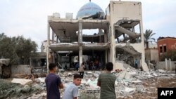 Palestinian stare at a mosque-turned-shelter in Deir al-Balah in the central Gaza Strip, heavily damaged in an Israeli strike during the night of Oct. 6, 2024.