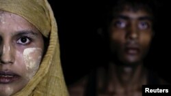 A woman makes her way to the shore as hundreds of Rohingya refugees arrive under the cover of darkness by wooden boats from Myanmar to Shah Porir Dwip, in Teknaf, near Cox's Bazar in Bangladesh, Sept. 27, 2017.