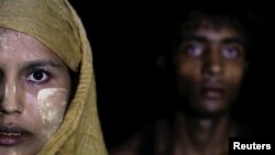 A woman makes her way to the shore as hundreds of Rohingya refugees arrive under the cover of darkness by wooden boats from Myanmar to Shah Porir Dwip, in Teknaf, near Cox's Bazar in Bangladesh, Sept. 27, 2017.