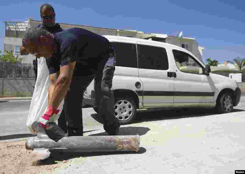 An Israeli police explosives expert displays for the media the remains of a neutralised rocket fired by Palestinian militants in Gaza after it landed in a house in the southern town of Sderot, July 3, 2014.