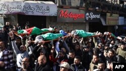 FILE - Mourners carry the flag-draped bodies of Palestinians killed during an Israeli raid in Jenin in the occupied West Bank, during their funeral on January 7, 2024.