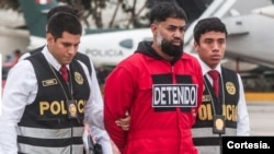 Vistiendo un traje rojo y esposado fue expulsado de Perú, Ángel García Hernández, alias “El Barbas”, vinculado al Tren de Aragua, el 17 de octubre de 2024 (Cortesía Policía Nacional de Perú)