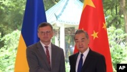 Menteri Luar Negeri Ukraina Dmytro Kuleba (kiri), berfoto bersama Menteri Luar Negeri China Wang Yi sebelum pertemuan di kota Guangzhou, China selatan, Rabu, 24 Juli 2024. (Lu Hanxin/Xinhua via AP)