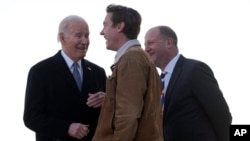President Joe Biden greets Colorado Gov. Jared Polis, right, and Denver Mayor Mike Johnston as he arrives on Air Force One at Denver International Airport, Nov. 28, 2023, in Denver.